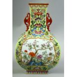 A CHINESE GREEN GROUND FAMILLE ROSE PORCELAIN VASE with moulded twin handles, the body decorated