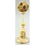A CHINESE CARVED IVORY PUZZLE BALL ON STAND, the carved floral ball elevated upon a finely carved