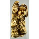 A JAPANESE CARVED IVORY NETSUKE of a man holding a mask, an inquisitive child at his feet, signed to