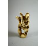 A JAPANESE CARVED IVORY NETSUKE of a sage holding a scroll seated on a rearing horse, signed to