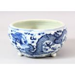 A CHINESE BLUE & WHITE PORCELAIN DRAGON BRUSH POT - with tripod feet, depicting dragons chasing