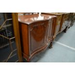 A mahogany serpentine fronted two door cabinet.
