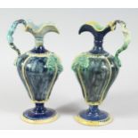 A GOOD PAIR OF FAIENCE POTTERY EWERS with ropework decoration and mermaid handles. 11ins high.