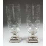 A PAIR OF CUT GLASS HURRICANE LAMPS on square bases. 15ins high