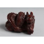 A JAPANESE CARVED WOOD NETSUKE DRAGON. 2ins. Signed.