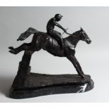 A BRONZE HORSE AND JOCKEY over the sticks, on a marble base.