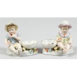 A PAIR OF PORCELAIN SALTS, boy and girl. 4ins high.