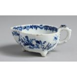 A BOW BUTTER BOAT on three feet painted with flowers and trailing leaves in underglaze blue, the