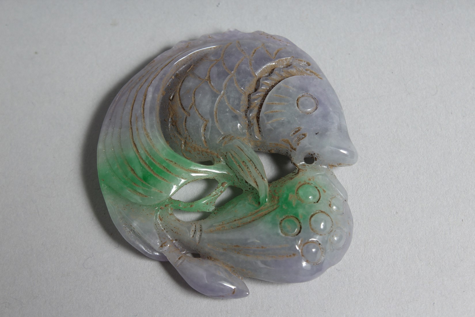 A CHINESE CARVED LILAC JADE FISH PENDANT.