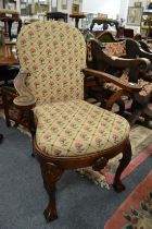 A Queen Anne style oak framed open armchair with needlework upholstered back and seat on shell