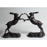 A PAIR OF BOXING HARES, 10ins high, on a marble base.