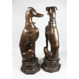A LARGE PAIR OF BRONZE SEATED DOGS on an octagonal base. 30ins high.