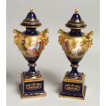 A SUPERB PAIR OF 19TH CENTURY VIENNA URNS VASES, COVERS AND STANDS, rich blue ground decorated in