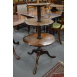 A George III mahogany three tier dumb waiter, the circular supports on a tripod base.