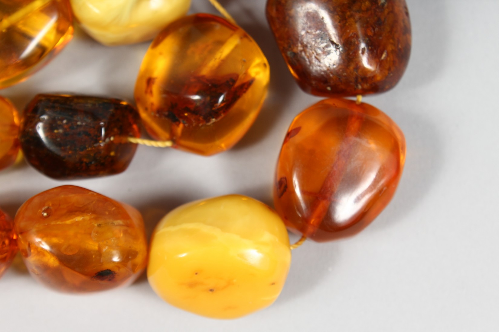 A STRING OF LARGE AMBER TYPE NATURALISTIC BEADS, various shapes and sixes, comprising 15 beads. - Image 3 of 4