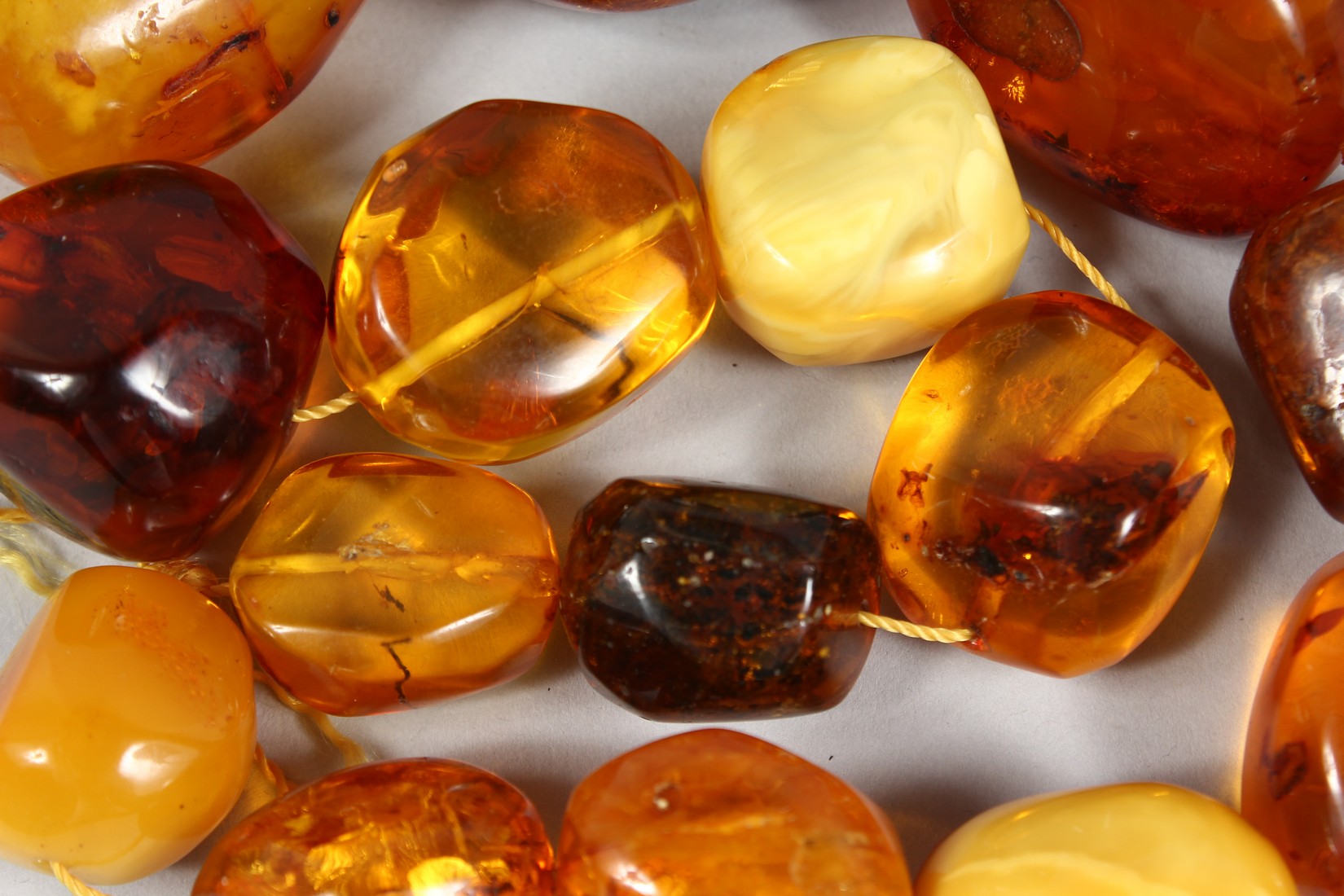 A STRING OF LARGE AMBER TYPE NATURALISTIC BEADS, various shapes and sixes, comprising 15 beads. - Image 2 of 4