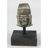 A CHINESE BRONZE HEAD SECTION raised on a wooden stand, the head measuring 6.5cm high