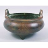 A CHINESE BRONZE TWIN HANDLE TRIPOD CENSER, with four character mark to base, 15cm diameter.