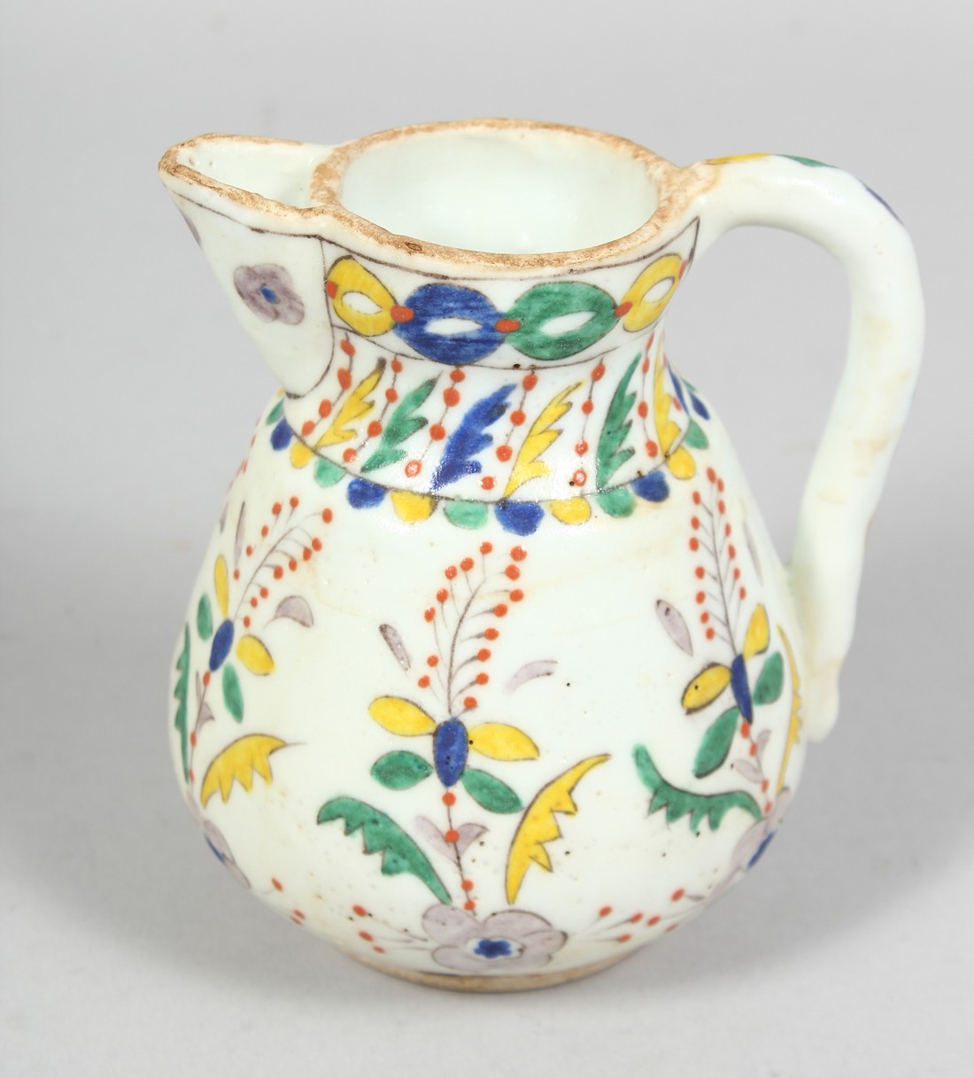 A SMALL TURKISH KUTAYHA POTTERY JUG, decorated with floral motifs, 12cm high.