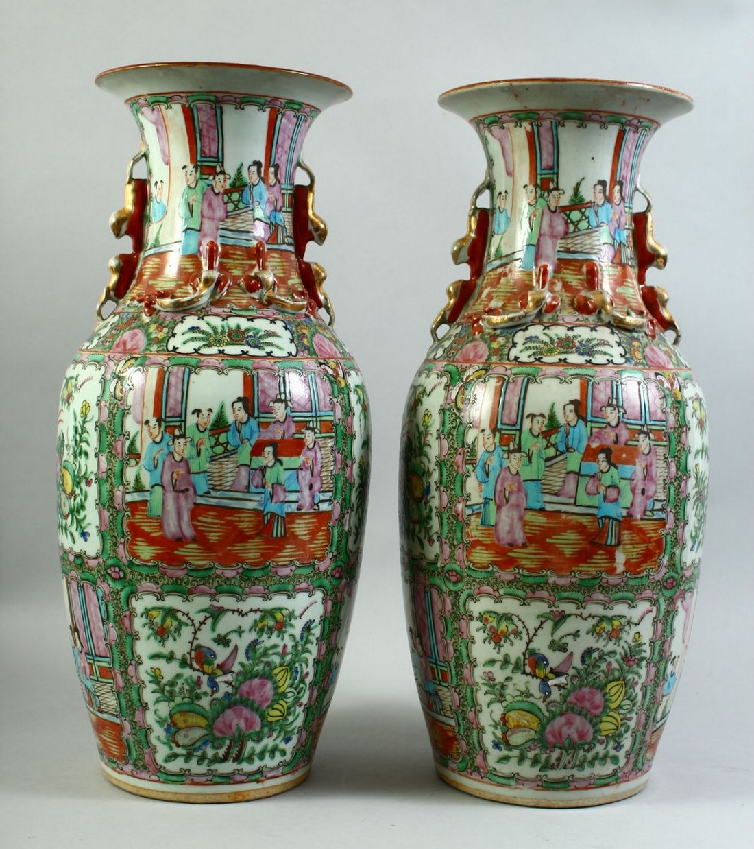 A PAIR OF CHINESE CANTON FAMILLE ROSE PORCELAIN VASES, the body of each painted with panels of