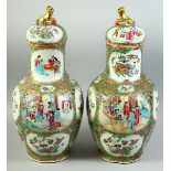 A PAIR OF CHINESE CANTON FAMILLE ROSE PORCELAIN VASES AND COVERS, painted with panels of figures