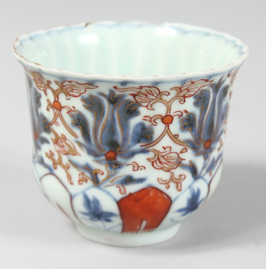 AN 18TH CENTURY JAPANESE IMARI PORCELAIN CUP, the interior of ribbed form, with floral motifs