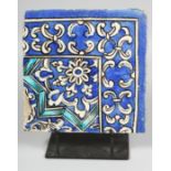 A PERSIAN GLAZED POTTERY CORNER-SECTION TILE painted blue and white foliate pattern and elevated