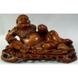A LARGE CARVED HARDWOOD HOTEI, on a fitted carved hardwood stand, the figure reclining with a