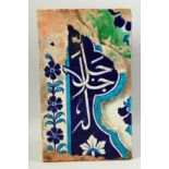 A LARGE ISLAMIC GLAZED POTTERY TILE PANEL with Qur'anic character to the centre. 38cm x 23cm