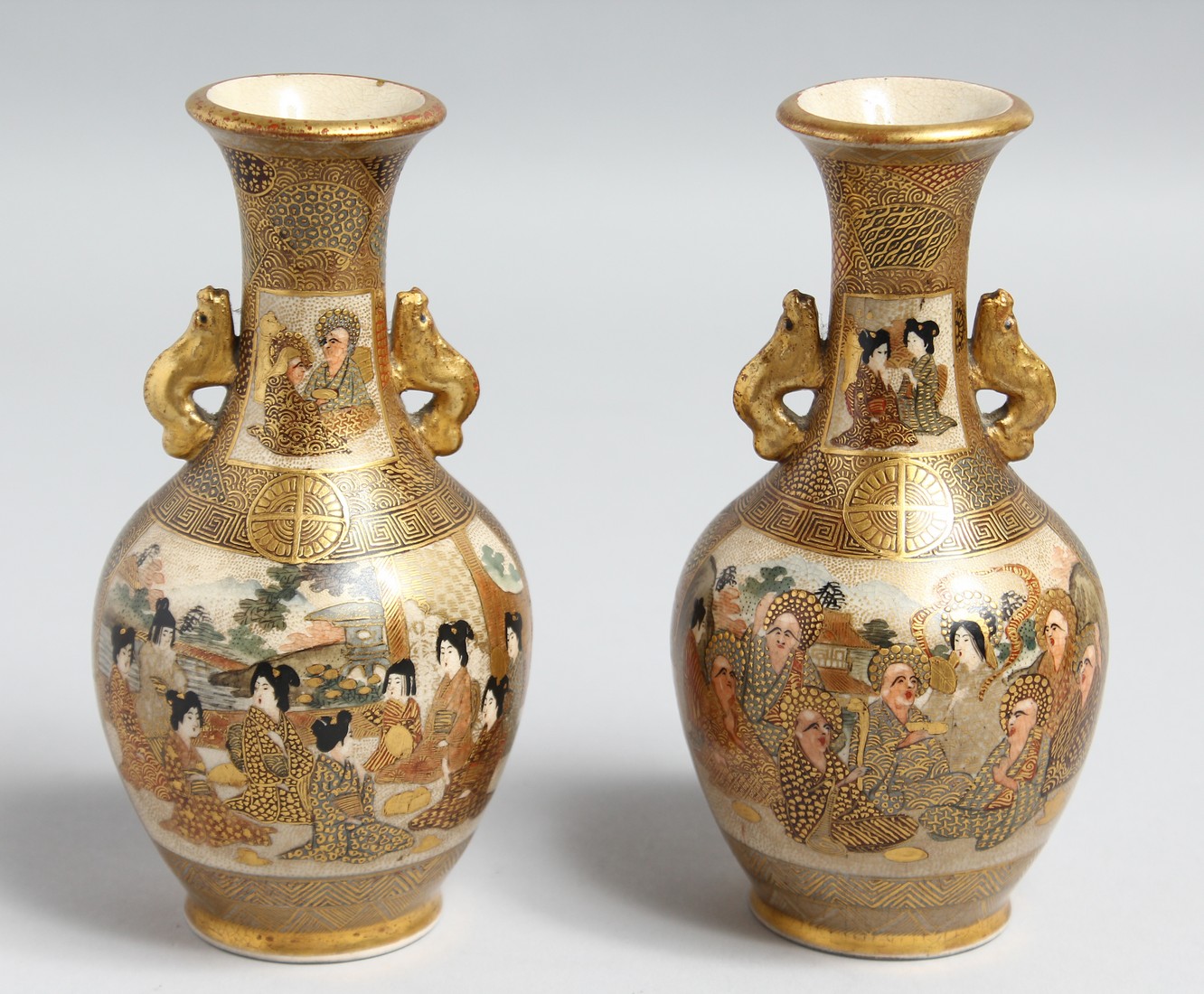 A PAIR OF SMALL JAPANESE SATSUMA PORCELAIN TWIN HANDLE VASES, painted with figures and gilt