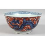 A CHINESE CORAL-RED GROUND BLUE AND WHITE PORCELAIN BOWL, the exterior decorated with dragons and