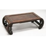 A CHINESE ROSEWOOD LOW TABLE WITH PANELLED TOP, supported on curving ends with pierced and carved