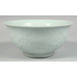 A CHINESE PALE CELADON PORCELAIN BOWL, the exterior with raised decoration depicting dragons and