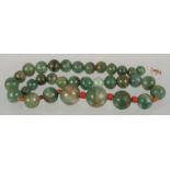 A SET OF GRADUATED JADE BEADS, the larger beads with small coral beads between.