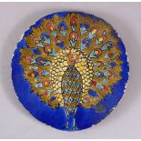 AN INDIAN CIRCULAR POTTERY TILE OF A PEACOCK, stood displaying its feathers, 20cm