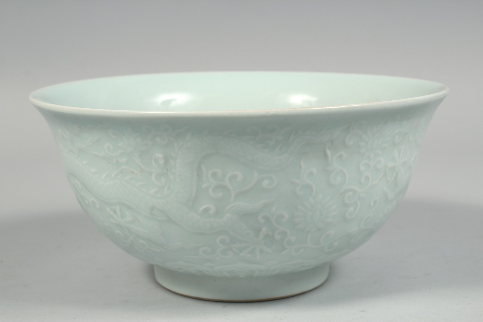 A CHINESE PALE CELADON PORCELAIN BOWL, the exterior with raised decoration depicting dragons and - Image 2 of 7
