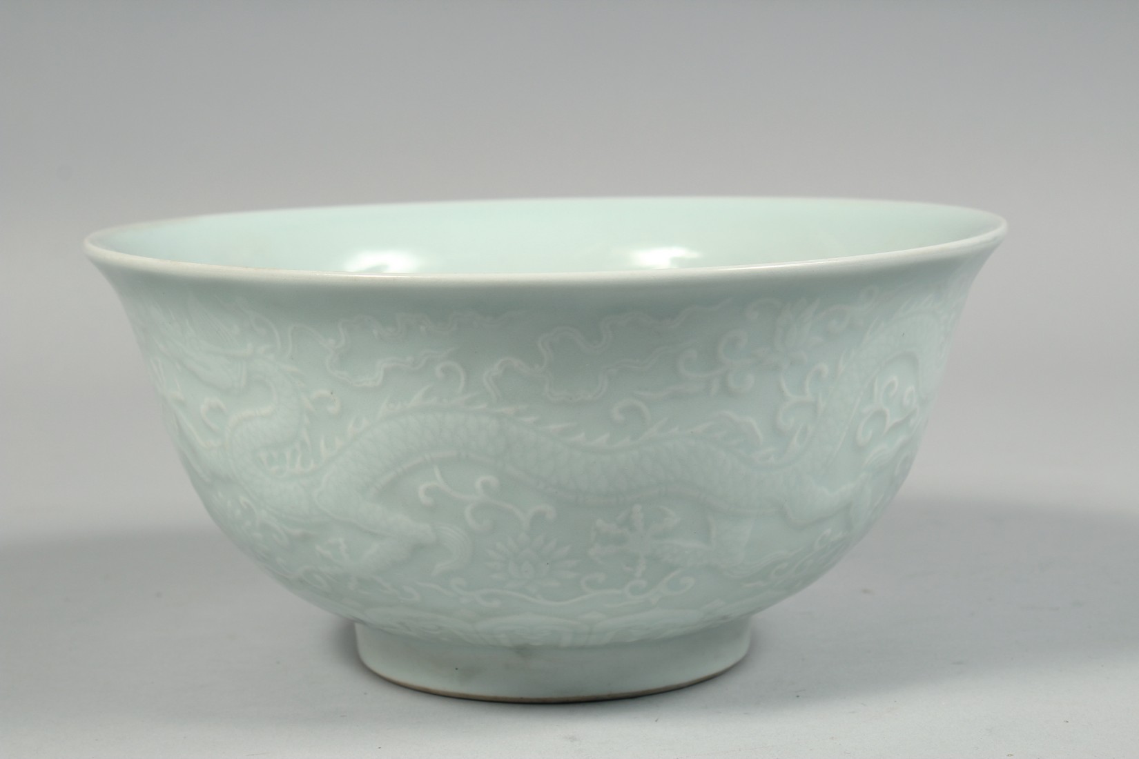 A CHINESE PALE CELADON PORCELAIN BOWL, the exterior with raised decoration depicting dragons and - Image 4 of 7