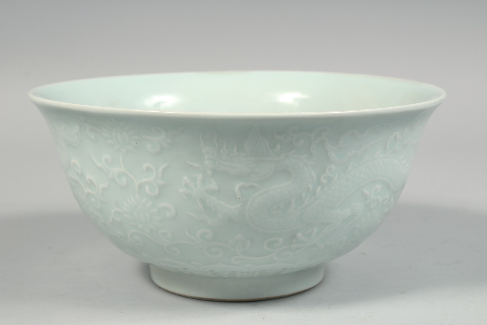 A CHINESE PALE CELADON PORCELAIN BOWL, the exterior with raised decoration depicting dragons and - Image 3 of 7