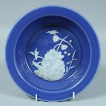 A CHINESE BLUE GROUND GLAZED CIRCULAR DISH with a white flower and birds. 8.5ins diameter.