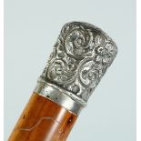 A VICTORIAN CANE with silver handle, repousse scroll decoration. London 1890. 35ins long.