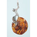 AN AMBER AND SILVER DESIGNER PENDANT.