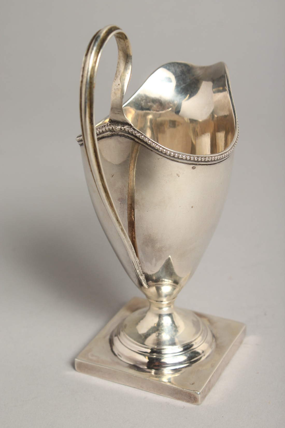 A GEORGE III SILVER HELMET SHAPED CREAM JUG, bead and edge on a square base. London 1784, Maker: - Image 4 of 9