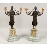 A PAIR OF EMPIRE DESIGN BRONZE AND GILT METAL, TWO BRANCH CANDELABRA held aloft by bronze