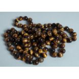 A STRING OF TIGER'S EYE BEADS.