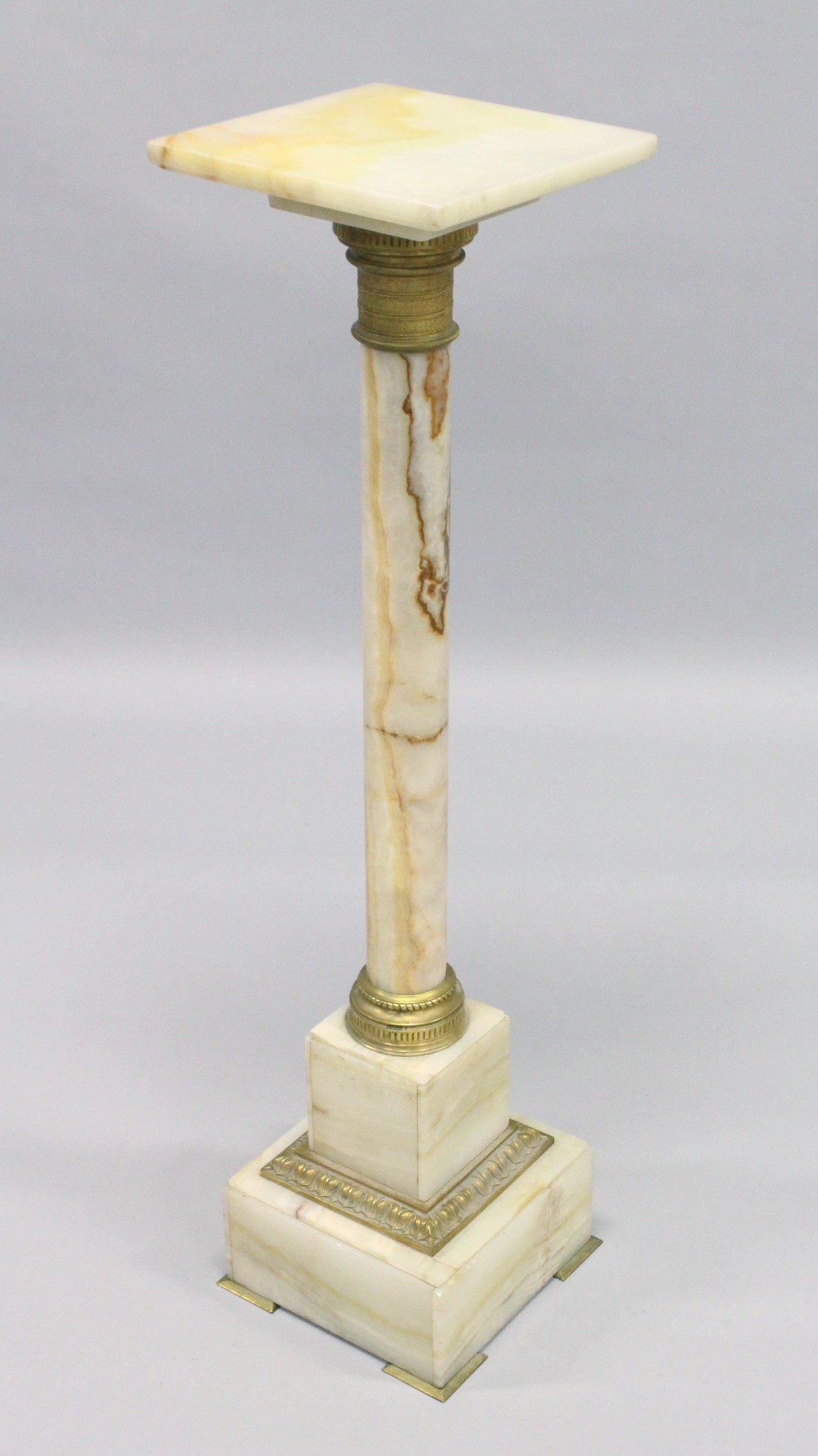 A GOOD ONYX AND BRASS SQUARE TOP COLUMN, the base on bracket feet. 3ft 3ins high, top 10ins square.