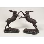 A PAIR OF BRONZE BOXING HARES on a marble base. 12ins high.