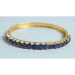 A GOOD 18CT GOLD SAPPHIRE SET BANGLE.