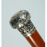 A VICTORIAN CANE with silver handle repousse with scrolls. London, 1887, 34ins long.