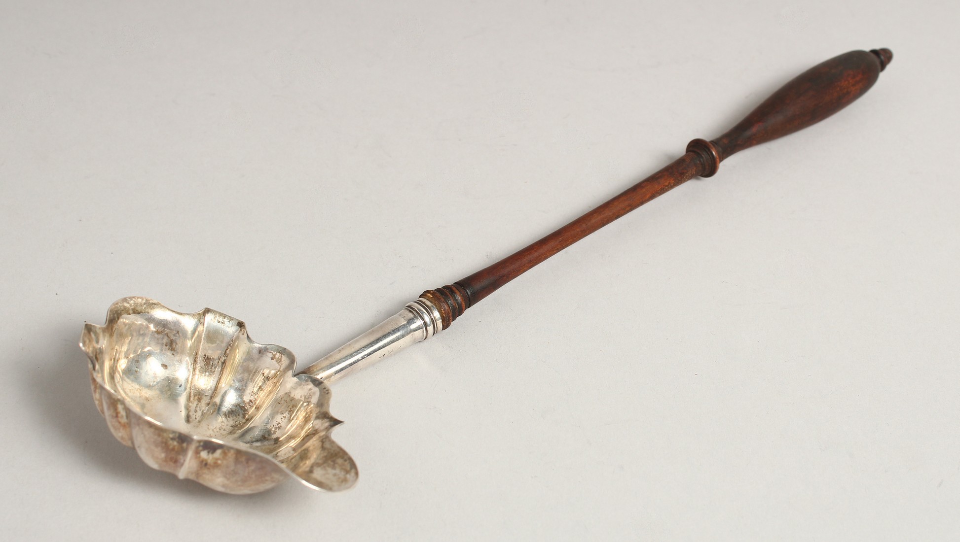 A GEORGE III SILVER PUNCH LADLE with turned wood handle. London 1772. Maker, W. B.