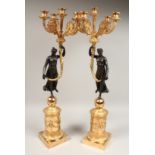 A PAIR OF EMPIRE DESIGN BRONZE AND GILT METAL, FIVE LIGHT CANDELABRA held aloft by bronze